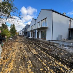 Mykhailo Marusiak - Rząd nowoczesnych domów jednorodzinnych z balkonami, świeżo po wykonaniu elewacji, z widocznymi śladami prac budowlanych na błotnistej drodze.