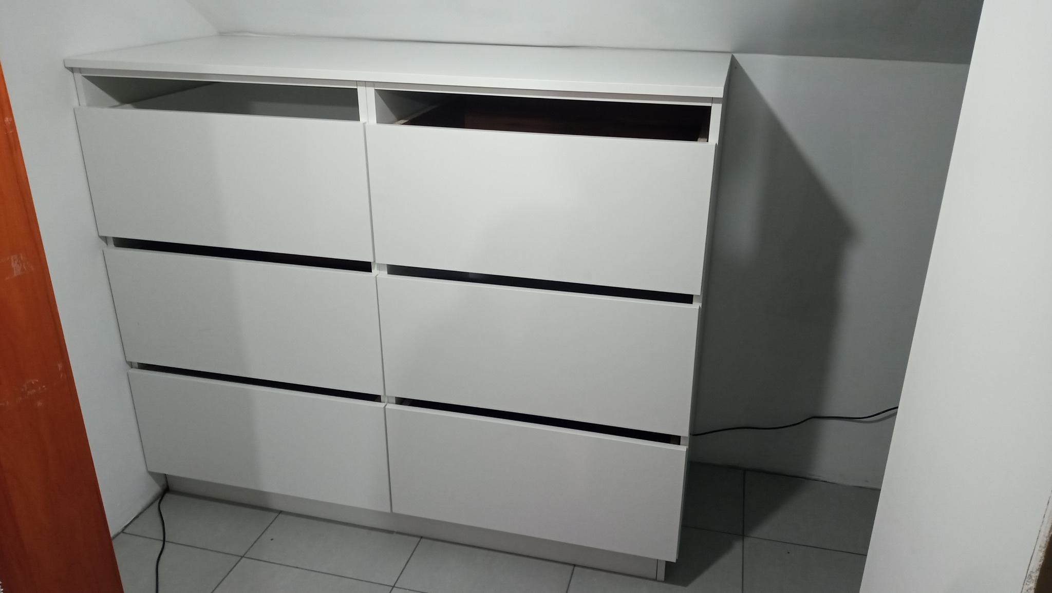 Biała szafa z szufladami na wymiar, idealna do przechowywania w pomieszczeniu ze skosami. Realizacja z Szczytnej.