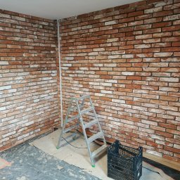 PPK PERFEKT 22 - Ściana wykończona czerwoną cegłą klinkierową, z widoczną drabiną i skrzynką narzędziową. Dekoracyjne wykończenie wnętrza w stylu industrialnym.
