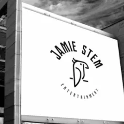 Czarno-białe zdjęcie billboardu z logo firmy Jamie Stem Entertainment, przedstawiające stylizowaną sowę i napis na tle nowoczesnego budynku.