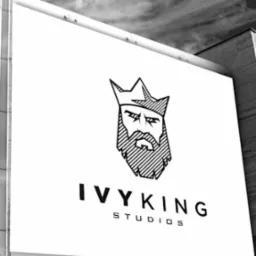 Czarno-białe zdjęcie szyldu 'IVYKING STUDIOS' z graficznym wizerunkiem brodatego króla w koronie, umieszczonego na tle pochmurnego nieba i fragmentu budynku.