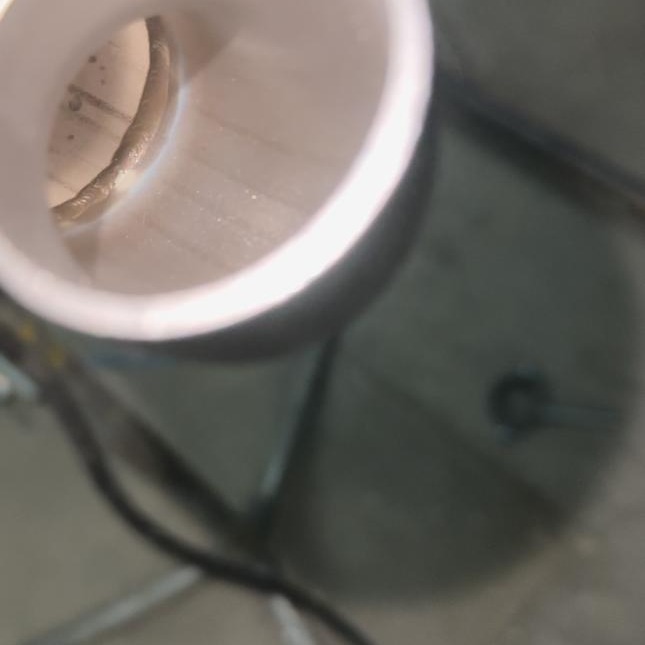 Wnętrze rury z widocznym spoiwem po spawaniu, uchwycone pod nietypowym kątem. Widoczne ślady obróbki i niedoskonałości spoiny. Szary odcień metalu.