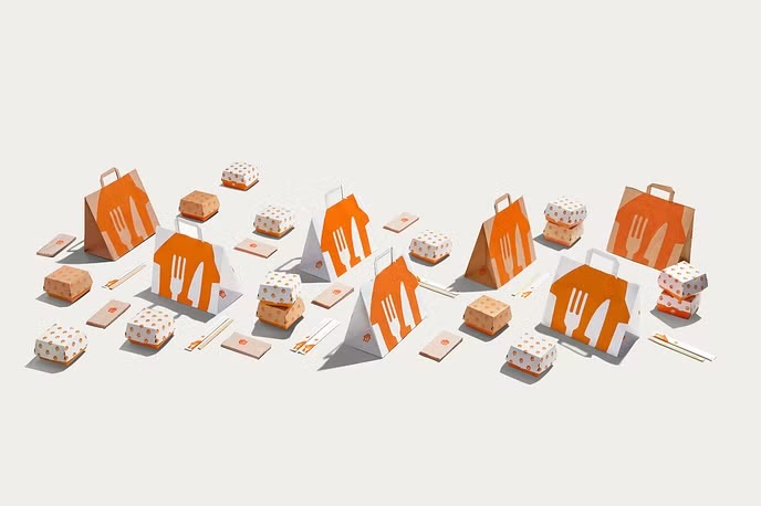 Rozłożony zestaw opakowań do dań na wynos z pomarańczowym logo sztućców: torby papierowe, pudełka kwadratowe i prostokątne, pałeczki. Minimalistyczne ujęcie na białym tle.