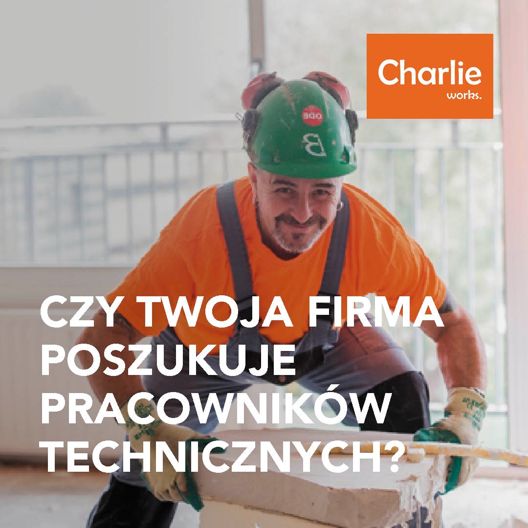 Pracownik techniczny z uśmiechem we Wrocławiu, w kasku i ubraniu roboczym, wykonuje prace budowlane. Reklama firmy Charlie works.