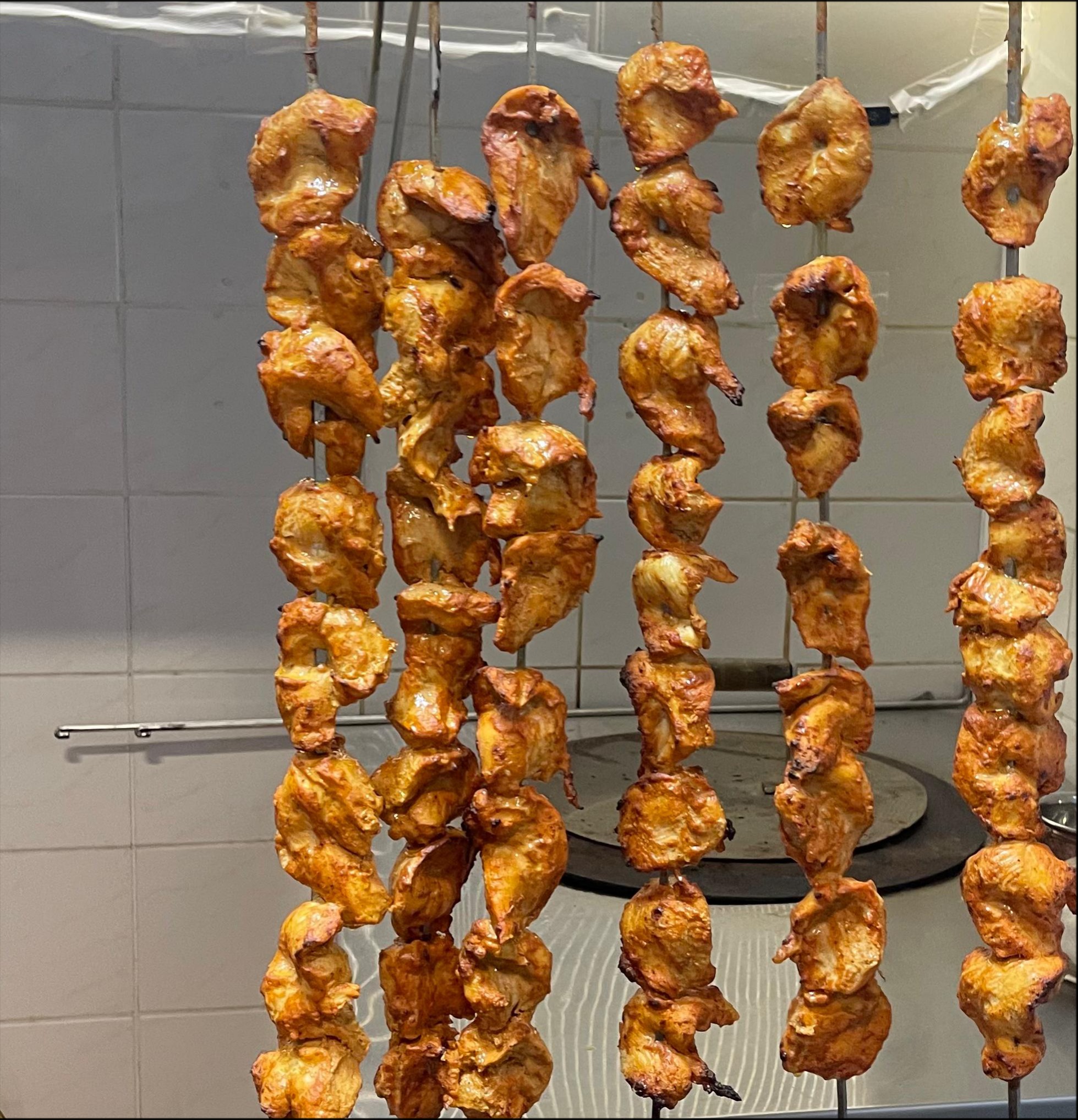 Aromatyczne, grillowane kawałki kurczaka na metalowych szpadkach, gotowe do serwowania. Widoczne ślady grillowania i apetyczny wygląd mięsa.