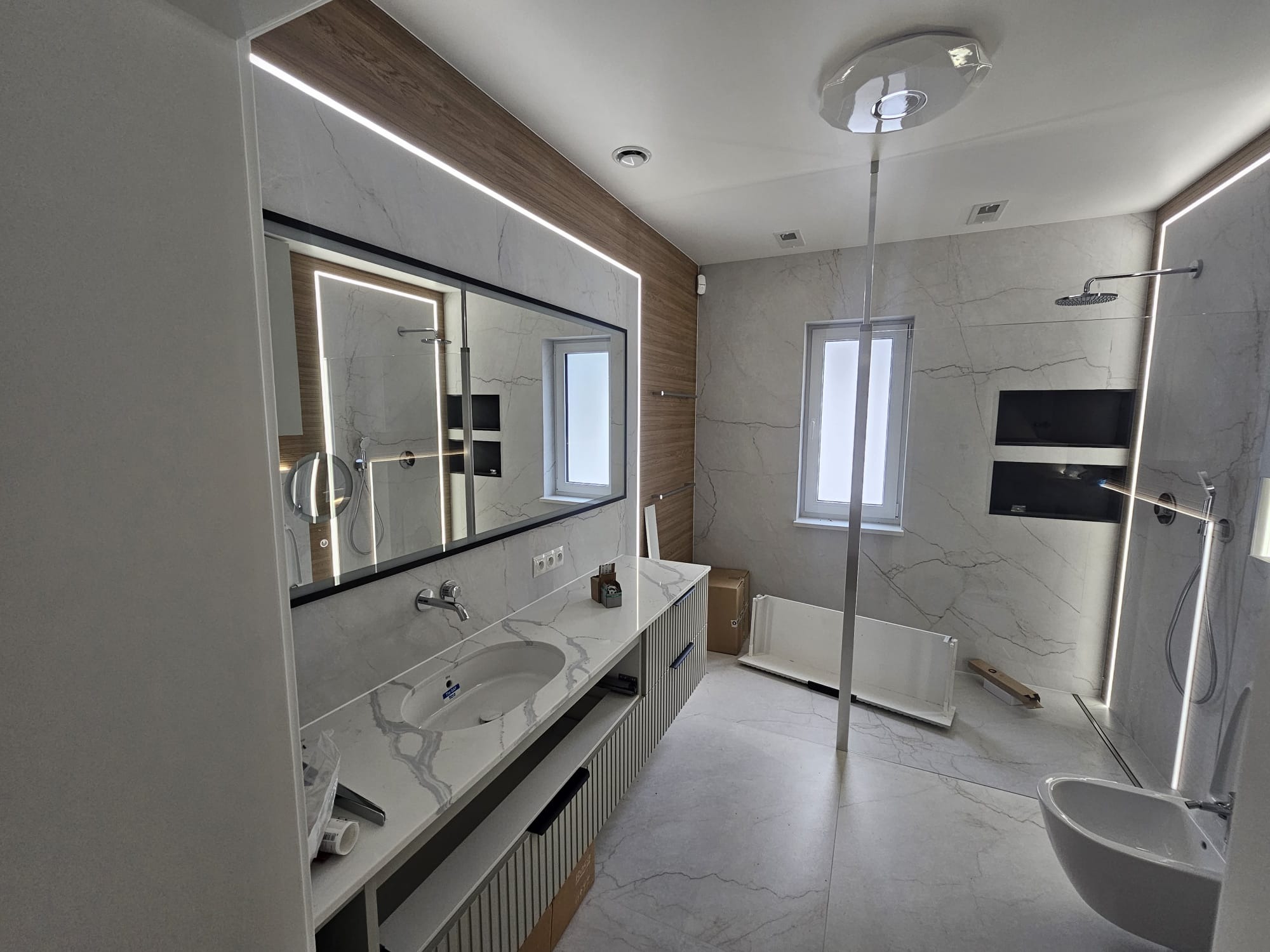 Nowoczesna łazienka po remoncie w Słubicach: marmurowe płytki, podświetlane lustro, wisząca toaleta i bidet. Minimalistyczny design z elementami drewna.