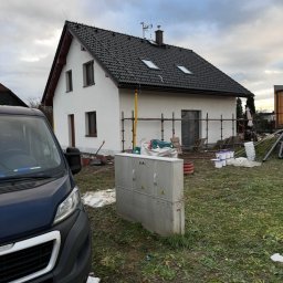 KORTIN - Ocieplony dom jednorodzinny po remoncie elewacji w Cieszynie, z widocznymi rusztowaniami i samochodem dostawczym. Świeżo pomalowana fasada w neutralnym odcieniu.