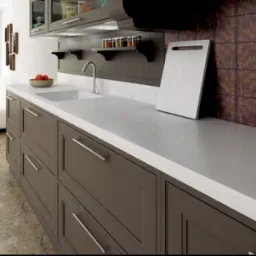 Nowoczesna kuchnia w Łosiowie z brązowymi szafkami, białym blatem i rdzawymi płytkami. Na blacie deska do krojenia i miska z owocami. Minimalistyczny design.