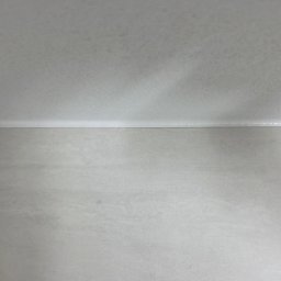 MIDEX - Gładka, szara ściana po szpachlowaniu i malowaniu, widok z dołu, z delikatnym cieniem na suficie. Minimalistyczne wykończenie wnętrza.