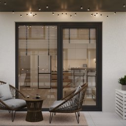 TARBAEV ARCHITECTS Eugeniusz Tarbayev - Przytulny balkon z rattanowymi fotelami, stolikiem kawowym i dekoracyjnymi lampkami. Widok na wnętrze mieszkania przez duże, przeszklone drzwi balkonowe.