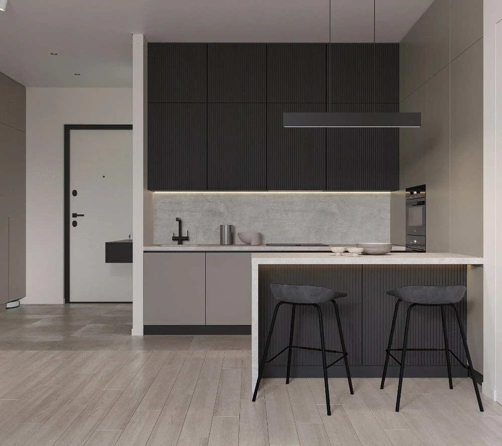 Minimalistyczna kuchnia w odcieniach szarości z czarnymi akcentami, oświetleniem LED i dwoma stołkami barowymi. Widok na wejście do mieszkania.