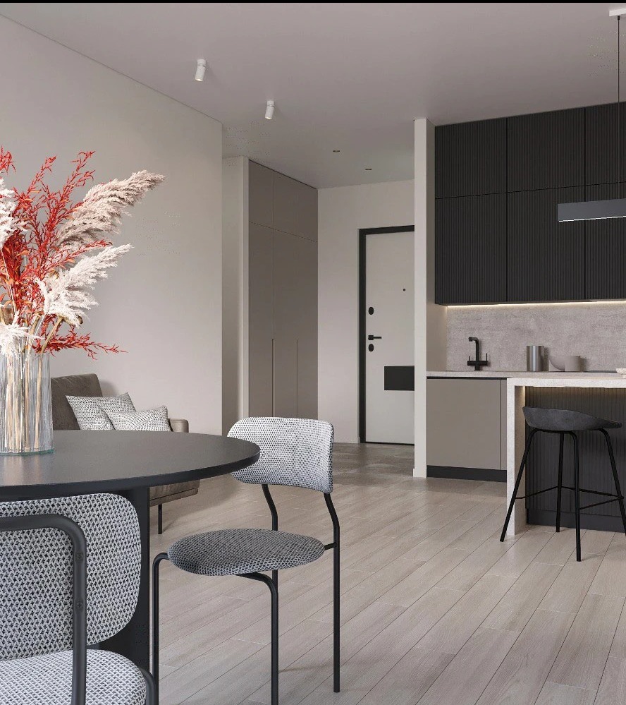 Nowoczesne wnętrze: stół z krzesłami na pierwszym planie, za nim aneks kuchenny z barkiem i salon z sofą, całość w stonowanej kolorystyce.