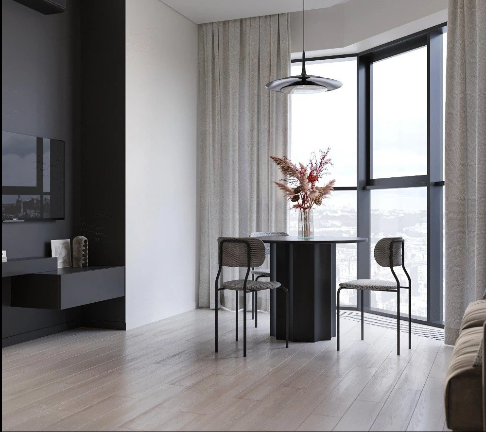 Minimalistyczna jadalnia z okrągłym stołem na tle okna panoramicznego. Szare krzesła, drewniana podłoga i designerska lampa tworzą spójną całość.