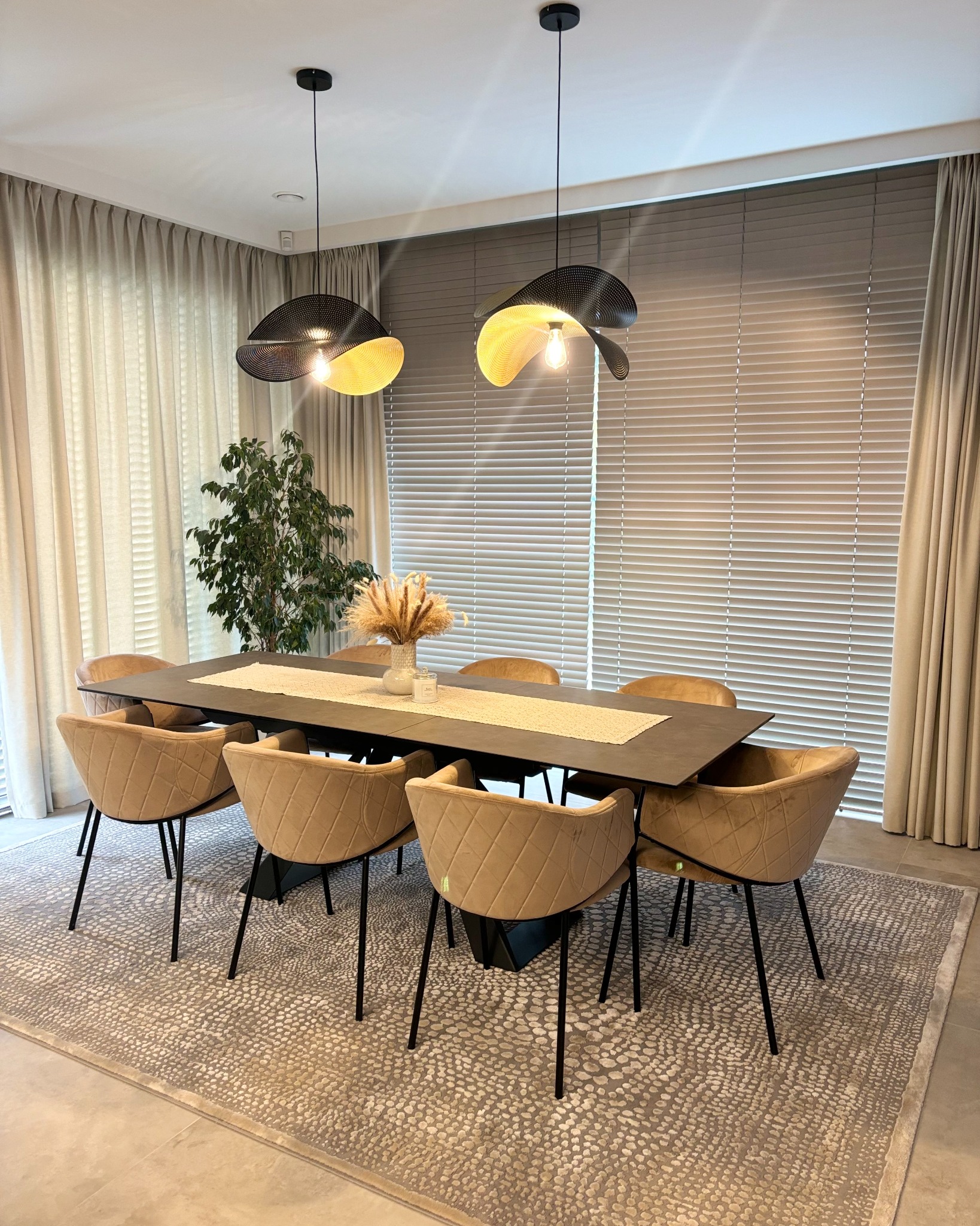 Eleganckie, poziome żaluzje aluminiowe w odcieniach beżu w nowoczesnym wnętrzu jadalni z designerskimi lampami i beżowymi krzesłami.