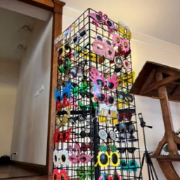 Stojak z rekwizytami imprezowymi: okulary w kształcie flamingów, kwiatów, piwa. Różnorodność wzorów na przyjęcie.