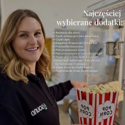 OLSOUND Wiktor Olszewski - Uśmiechnięta kobieta z popcornem na tle listy dodatków eventowych, w tym animacji dla dzieci i fotobudki, z logo Olsound na bluzie. Atrakcje na imprezę.