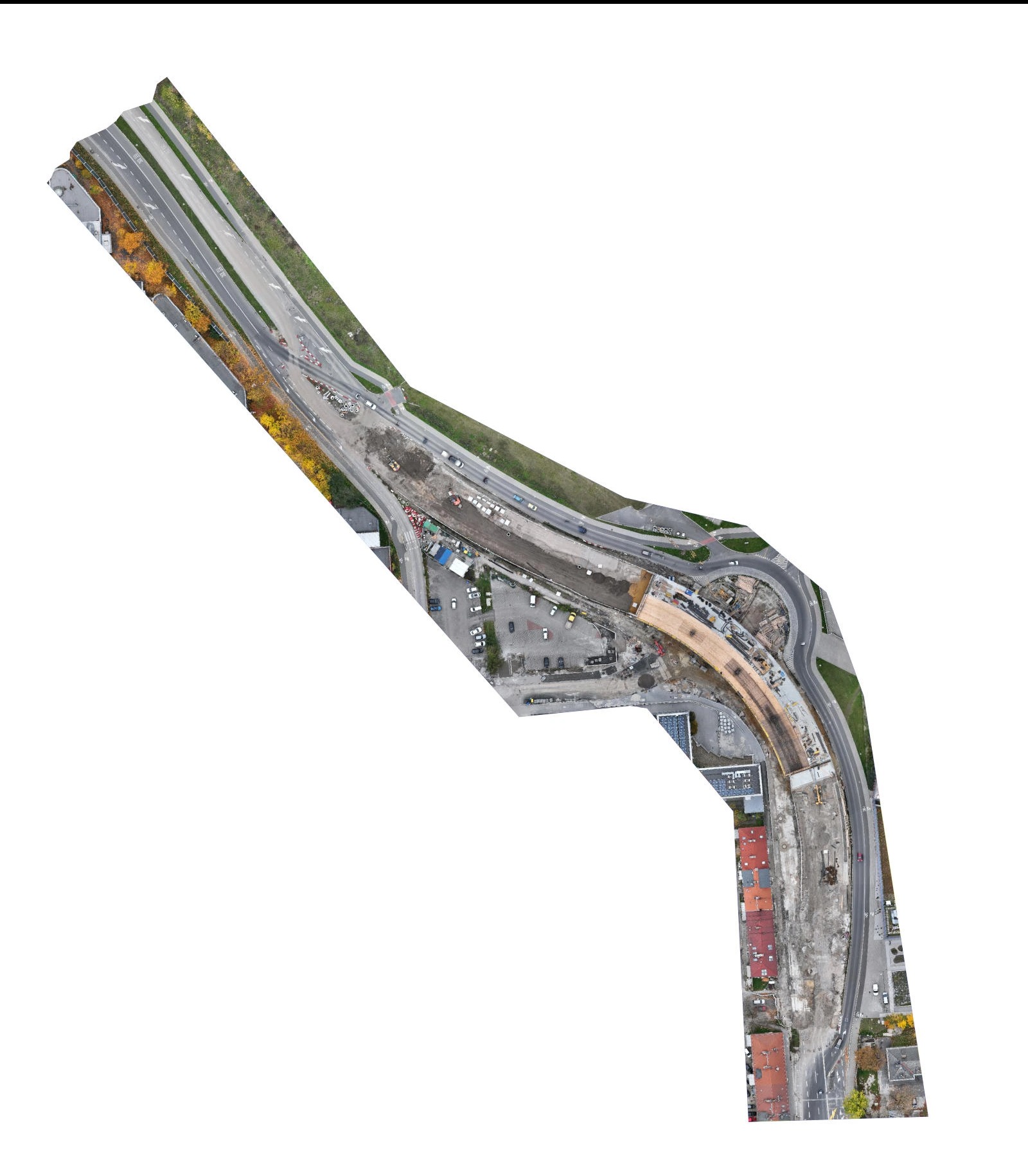 Zdjęcie z drona przedstawia budowę drogi z rondem, widoczne maszyny budowlane i fragmenty istniejącej infrastruktury drogowej. Ujęcie z góry, w dzień.