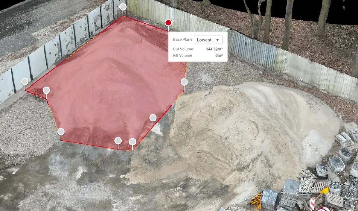 Pomiar objętości hałdy piasku z użyciem oprogramowania. Widoczny obrys z zaznaczonym polem 344.52m3. W tle ogrodzenie i drzewa. Perspektywa z góry.