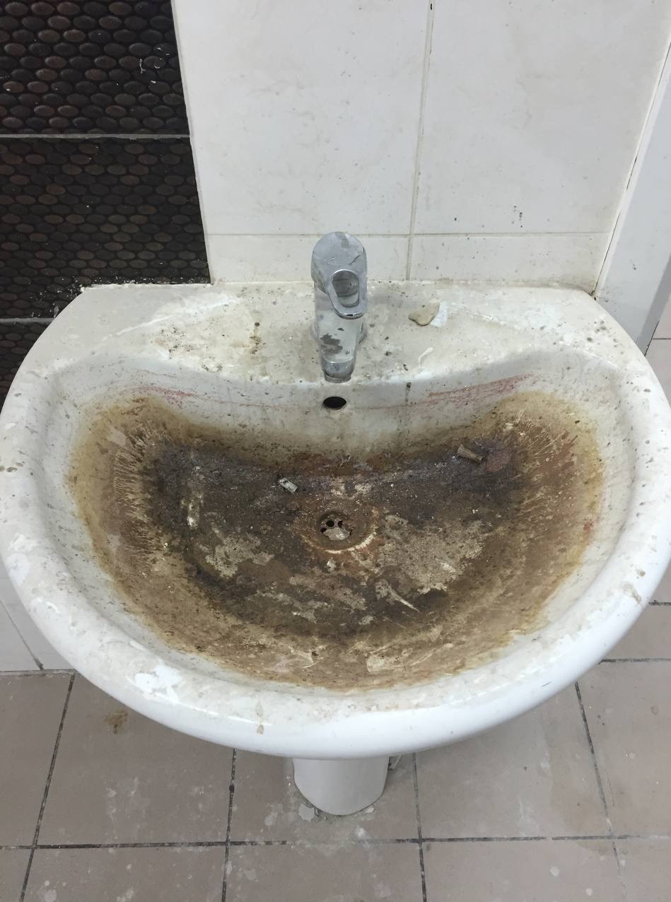 Zaniedbana, brudna umywalka z osadami i plamami. Widoczne zabrudzenia na baterii i płytkach. Potrzebne gruntowne czyszczenie.