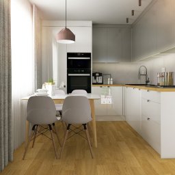 TMSYS sp. z o.o. - Jasna kuchnia z drewnianą podłogą i białymi meblami, oświetlona naturalnym światłem. Stół z krzesłami w minimalistycznym stylu. Widoczne AGD i elementy dekoracyjne.