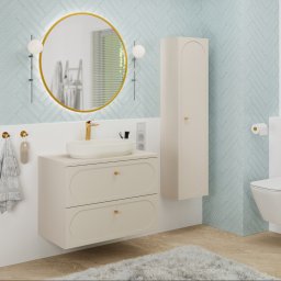 TMSYS sp. z o.o. - Elegancka łazienka w Krakowie: błękitne płytki ułożone w jodełkę, okrągłe lustro w złotej ramie, beżowa szafka pod umywalką i wisząca toaleta. Nowoczesny design.