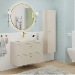 Elegancka łazienka w Krakowie: błękitne płytki ułożone w jodełkę, okrągłe lustro w złotej ramie, beżowa szafka pod umywalką i wisząca toaleta. Nowoczesny design.