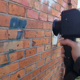 BM Laser Bartosz Małolepszy - Czyszczenie ceglanej ściany z graffiti w Wieruszowie przy użyciu specjalistycznego sprzętu. Widoczne ślady farby przed usunięciem.