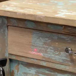 Fragment komody w stylu vintage, z widocznymi śladami użytkowania i laserowo czyszczonym fragmentem szuflady, ukazującym różnicę w wyglądzie.