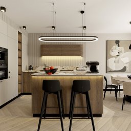 SANDROOM ARCHITEKTURA WNĘTRZ SANDRA MACULEWICZ - Elegancka kuchnia z wyspą oświetloną LED, drewniane akcenty, marmurowy blat i nowoczesne krzesła barowe. Minimalistyczny design z obrazem w tle.