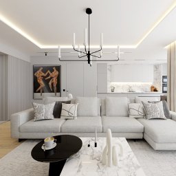 SANDROOM ARCHITEKTURA WNĘTRZ SANDRA MACULEWICZ - Nowoczesny salon z narożną sofą, czarnym stolikiem kawowym i marmurowym blatem, oświetlony designerską lampą wiszącą. W tle widoczna kuchnia i obraz na ścianie.