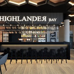 SANDROOM ARCHITEKTURA WNĘTRZ SANDRA MACULEWICZ - Nowoczesny projekt baru 'Highlander Bay' z ceglaną ścianą, czarnym barem z heksagonalnym wzorem i drewnianą podłogą. Widoczne wiszące lampy i butelki alkoholi.