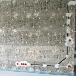 Ściana z izolacją, w której poprowadzone są kable elektryczne zabezpieczone pianką montażową i puszkami. Widoczne otwory pod gniazdka.