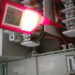 EL Mar MARCIN SOBCZAK - Czerwony miernik napięcia wskazuje 409V na listwie zaciskowej w szarej skrzynce elektrycznej. Widoczne kable i śruby mocujące.