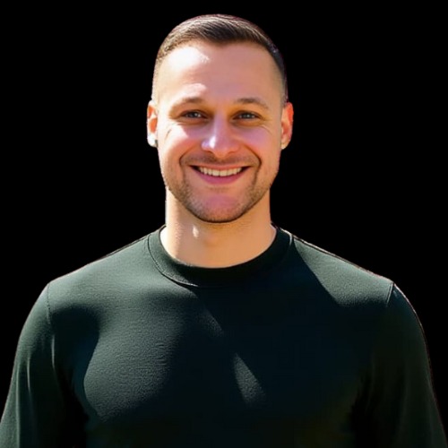 Uśmiechnięty mężczyzna z krótkimi włosami, ubrany w ciemnozieloną koszulkę, na czarnym tle. Widoczny portret od ramion w górę, z wyraźnym oświetleniem twarzy.