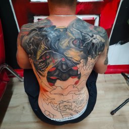 Pracownia Artystyczna Degenera - Mężczyzna z rozbudowanym tatuażem na plecach, częściowo w trakcie wykonywania. Widoczny etap tworzenia wzoru, kontrast między gotowym a szkicem.