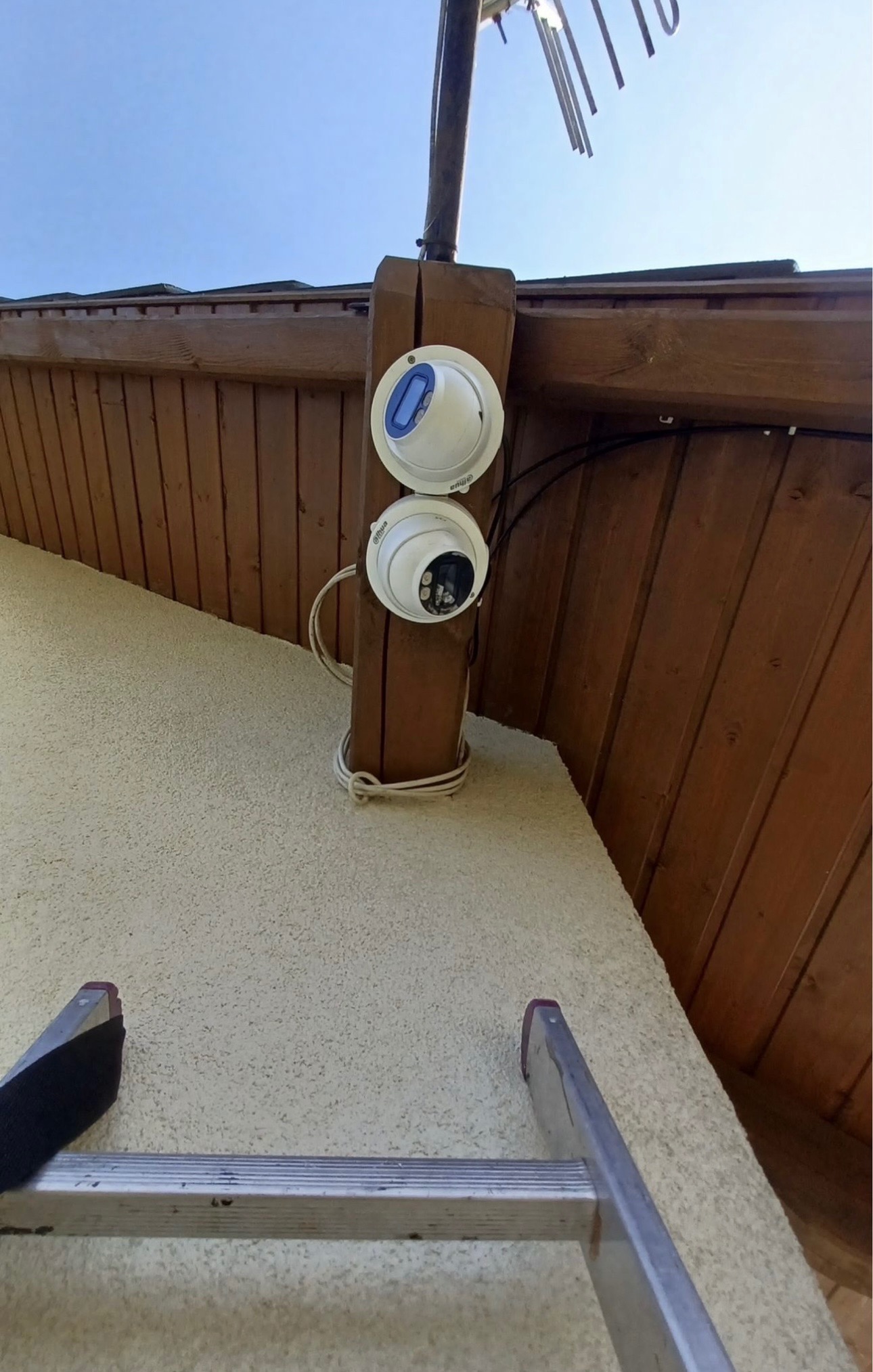 Dwie kamery monitoringu kopułkowe Dahua zamontowane na drewnianej konstrukcji pod dachem, widok z dołu, drabina oparta o ścianę.
