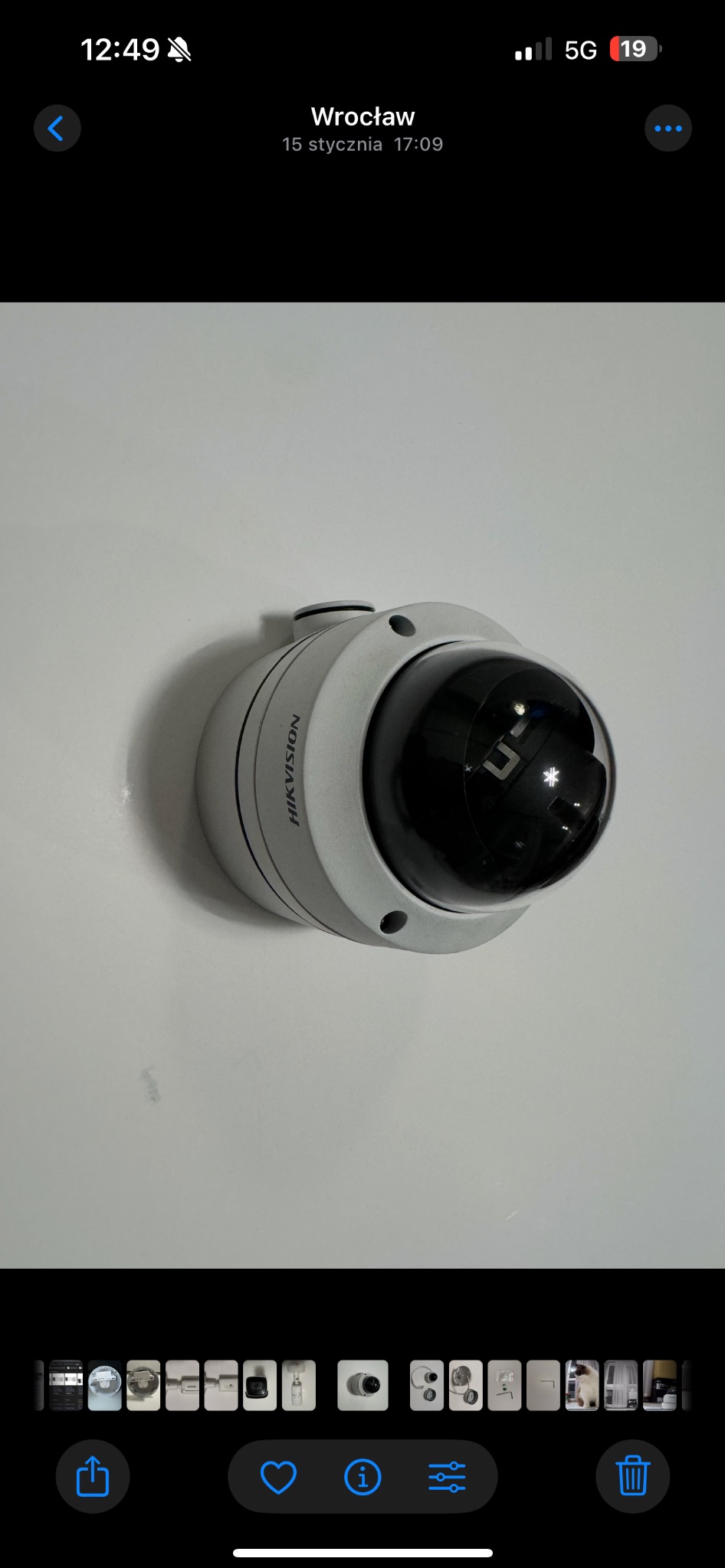 Kamera przemysłowa Hikvision typu 'dome' na jasnym tle. Widoczne otwory montażowe i logo producenta. Obiektyw kamery odbija światło.