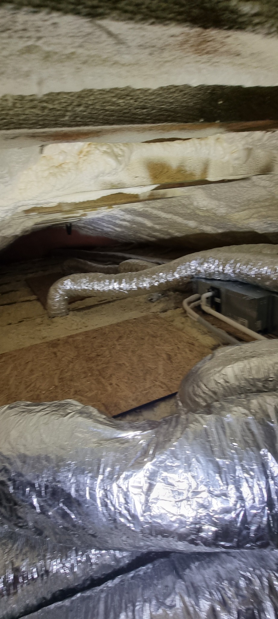 Szczegółowe ujęcie instalacji klimatyzacji w przestrzeni pod stropem, z widocznymi przewodami wentylacyjnymi i izolacją.