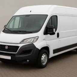 Biały samochód dostawczy Fiat Ducato na kostce brukowej, z widocznym logo marki na grillu. Auto gotowe do transportu, idealne do przeprowadzek.