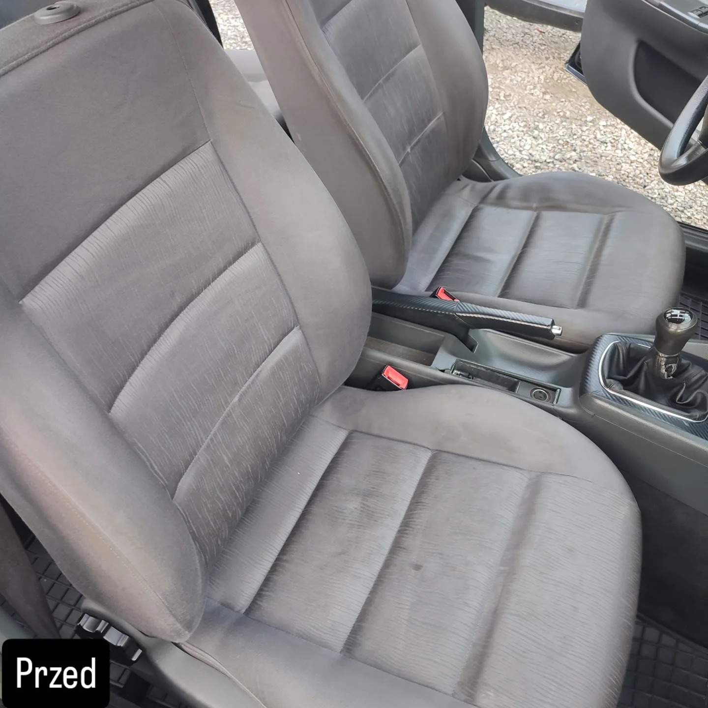 Szare, zabrudzone fotele samochodowe z tapicerką materiałową, widok z góry, oznaczone jako stan 'Przed' czyszczeniem. Widoczne detale wnętrza auta.