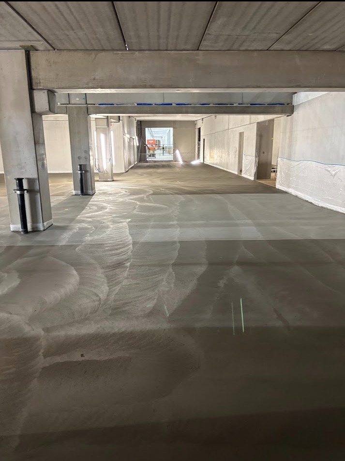 Wyrównana, szorstka powierzchnia betonowa w hali przemysłowej w Grodkowie. Widoczne ślady po zacieraniu mechanicznym, surowy beton, przygotowanie pod posadzkę.