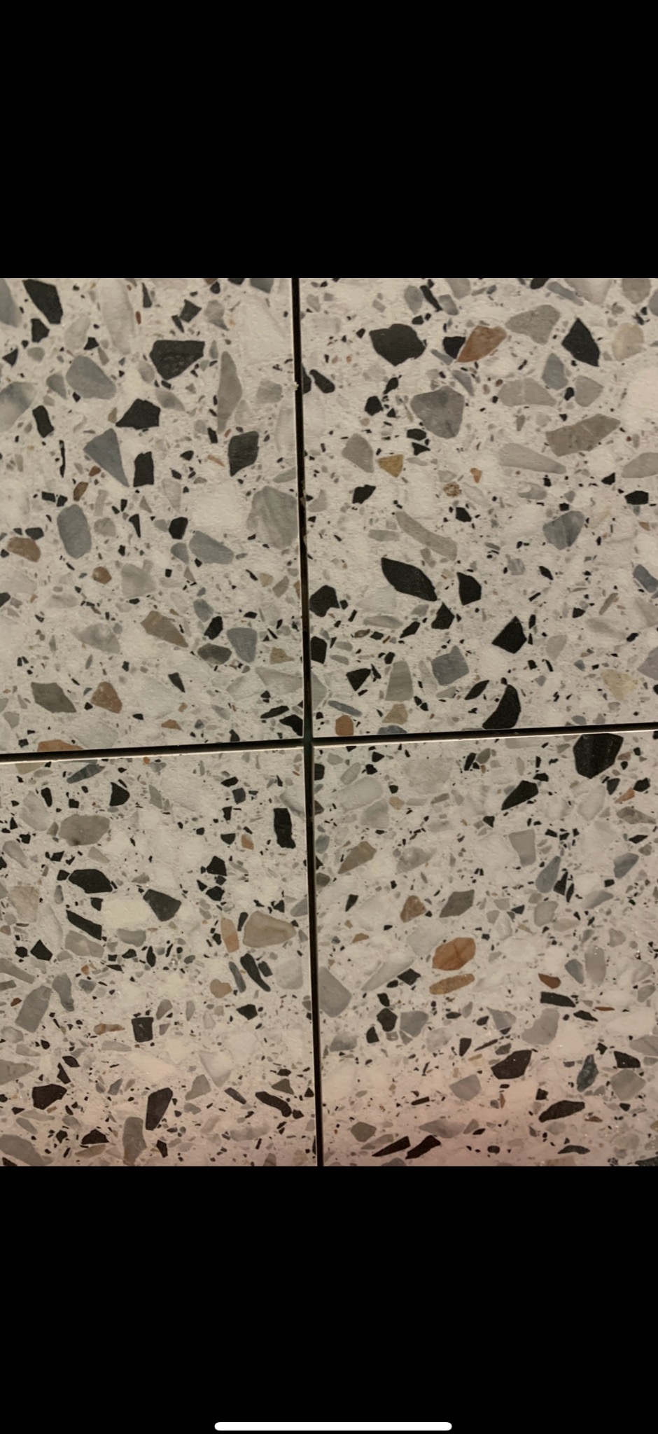 Zbliżenie na cztery płytki podłogowe w stylu lastryko, z widocznymi fugami. Płytki mają nieregularne, kolorowe wzory na białym tle. Minimalistyczny design.