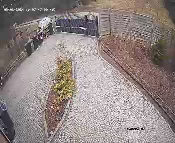 Ukończony podjazd z kostki granitowej w kształcie wachlarza, brama wjazdowa z metalu, ogrodzenie drewniane, widok z góry z kamery monitoringu.