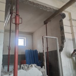 Robótka Na Luzie - Wnętrze w trakcie demontażu ściany, widoczne podpory stalowe, gruz i fragment okna. Prace remontowe w pomieszczeniu z usuniętymi fragmentami ścian.