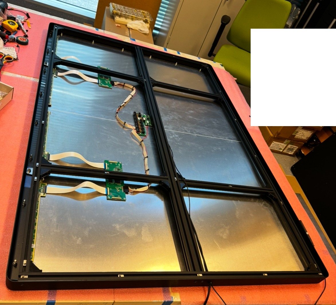 Konstrukcja ramy z podzespołami elektronicznymi i kablami, prawdopodobnie w trakcie montażu. Widoczne elementy PCB i taśmy połączeniowe.