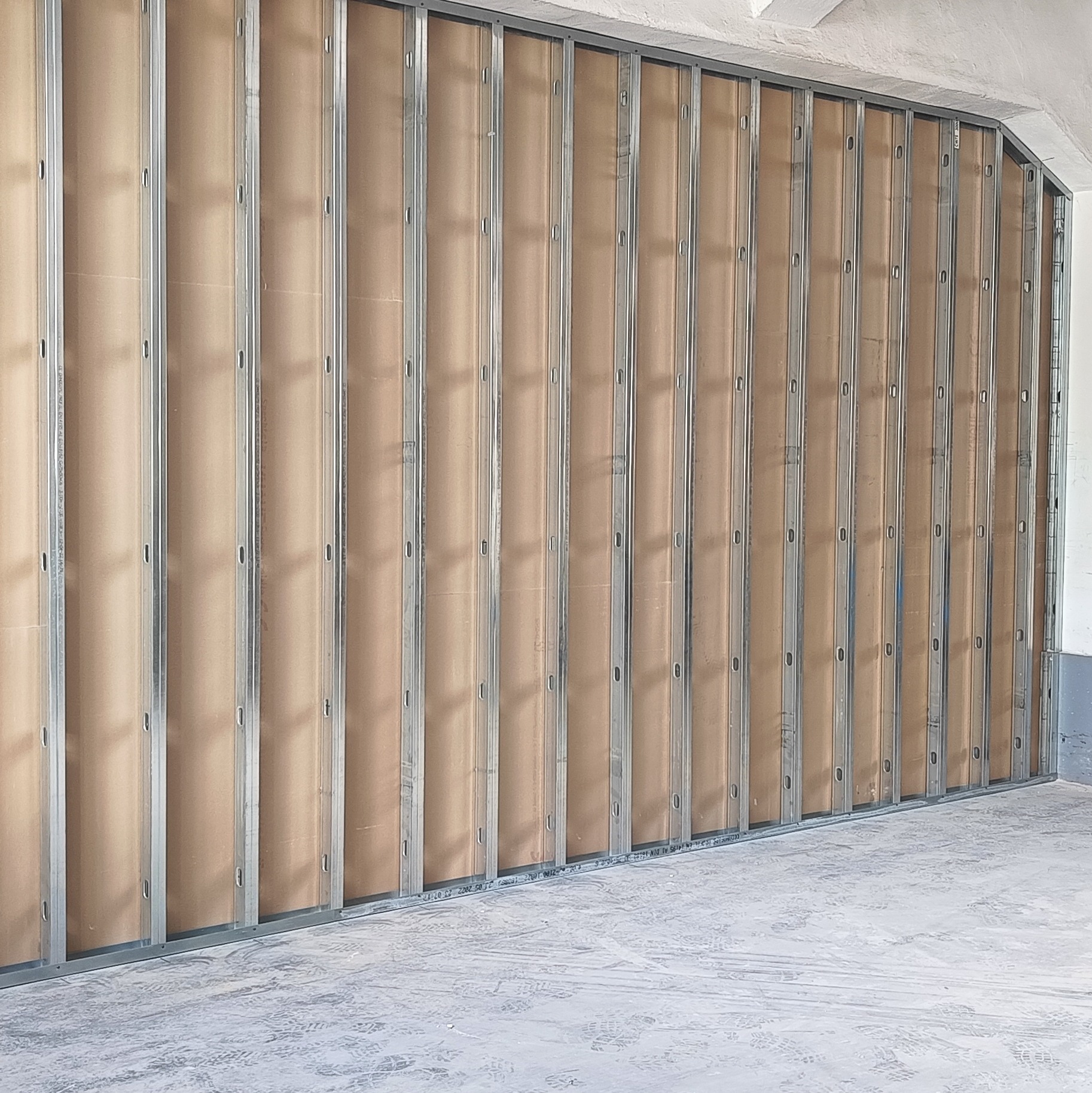 Konstrukcja ścianki działowej z profili stalowych i płyt karton-gips, widoczne mocowania, surowy stan podłoża. Przygotowanie do dalszych prac wykończeniowych.