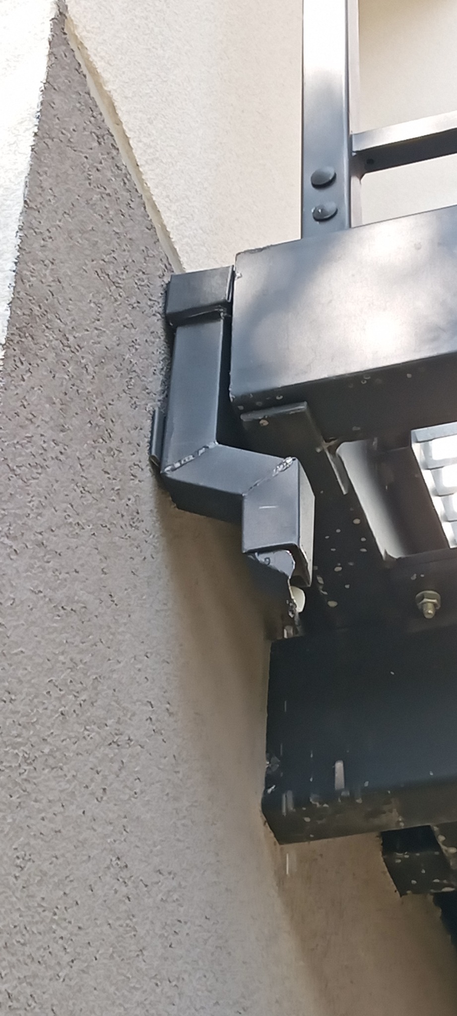 Rynienka z rurą spustową między schodami a budynkiem żeby zapobiec brudzeniu elewacji.