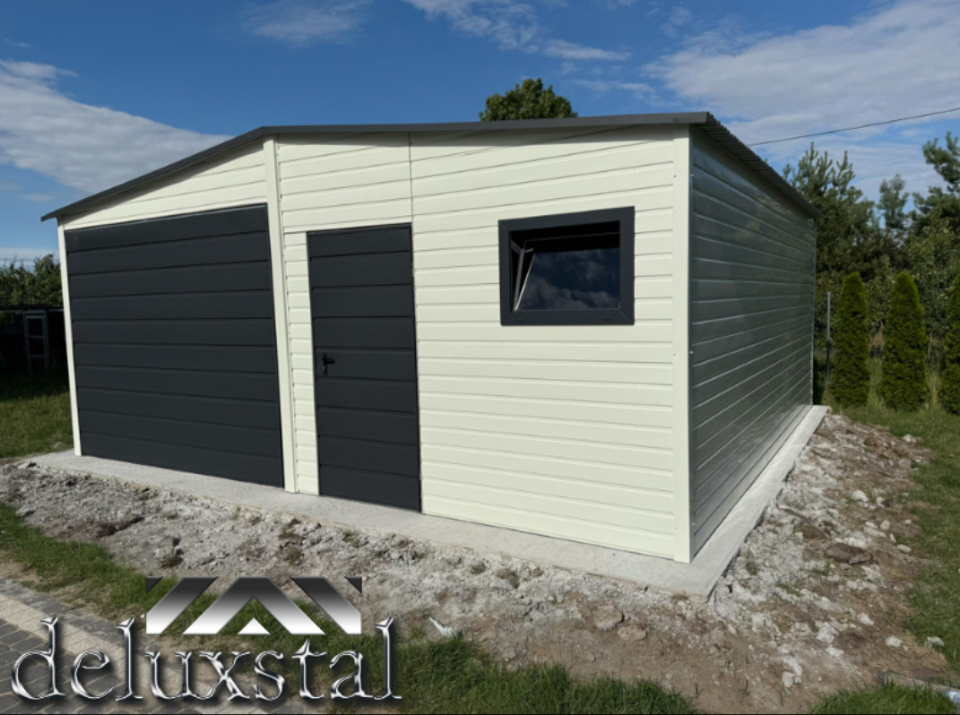 Dwukolorowy garaż blaszany z oknem, z grafitową bramą i drzwiami, na betonowej wylewce, otoczony zielenią. Widok z zewnątrz, w słoneczny dzień.