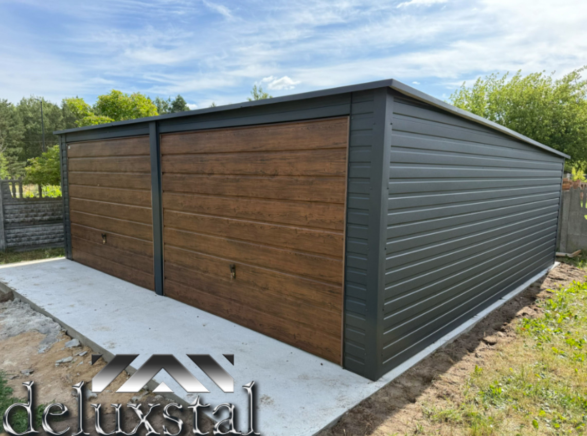 Dwustanowiskowy garaż blaszany z bramami imitującymi drewno, szara blacha, betonowa wylewka, widok z boku na tle zieleni i błękitnego nieba.