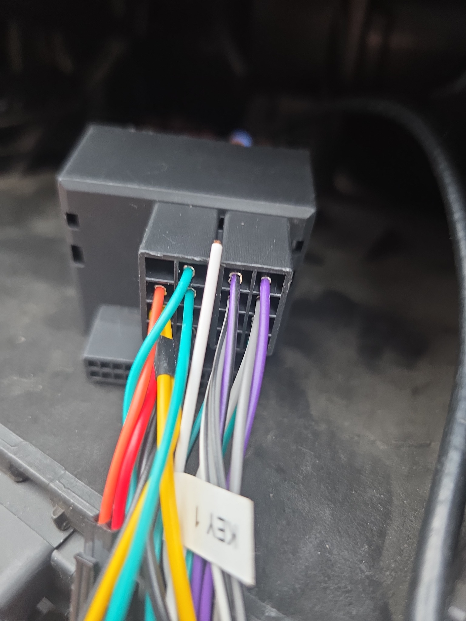 Czarna kostka z kolorowymi przewodami, etykieta 'KEY 1', prawdopodobnie instalacja elektryczna w samochodzie. Widok z bliska na złącze.